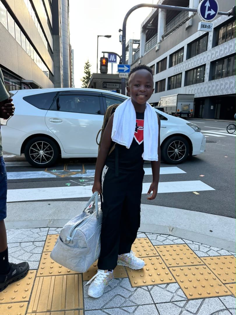 Prince smiling with luggage on an urban sidewalk