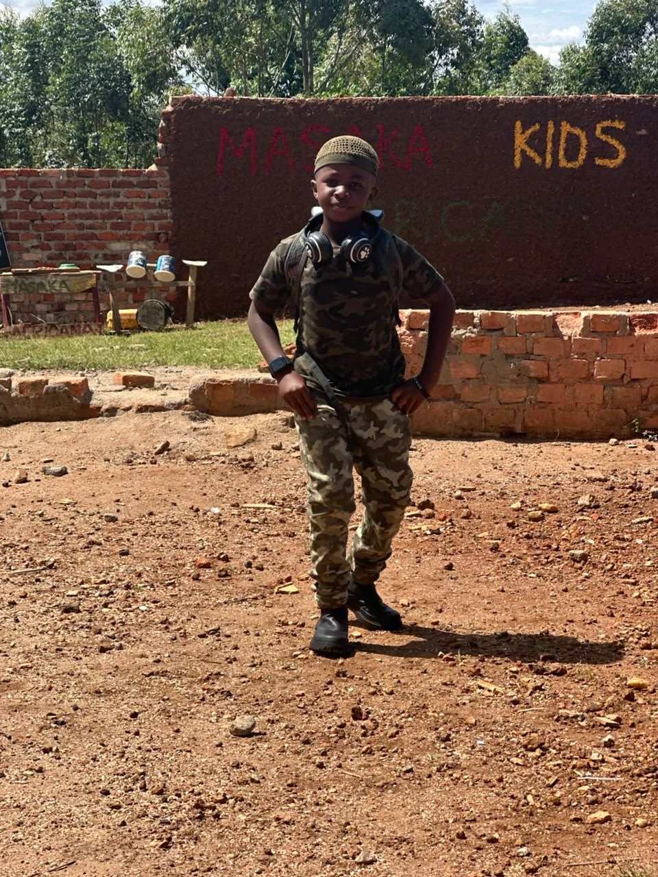 Prince posing confidently near Masaka Kids Africana sign